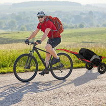 Person cycling with the Smart cargo bike trailer in tow on a country road