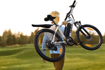 Person standing with the VARUN M24-1 electric mountain bike in white on a grassy field