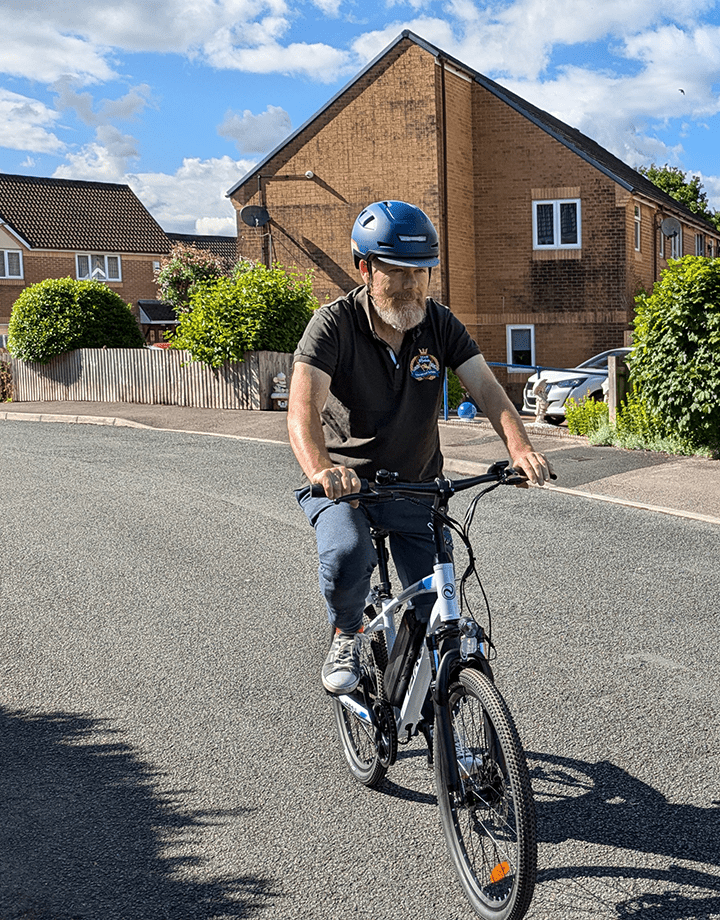 Man riding the VARUN M24-1 electric mountain bike in white wearing a helmet on a street