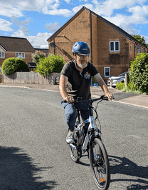 Man riding the VARUN M24-1 electric mountain bike in white wearing a helmet on a street