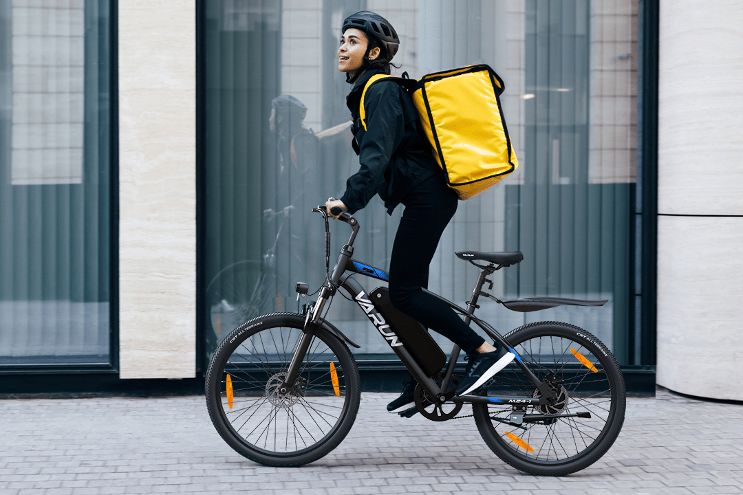 Person riding the VARUN M24-1 electric mountain bike in black wearing a helmet in the city