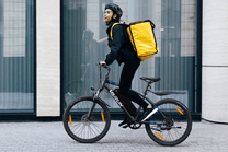Person riding the VARUN M24-1 electric mountain bike in black wearing a helmet in the city