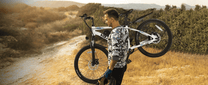 Man standing with the VARUN M24-1 electric mountain bike in white on a grassy field