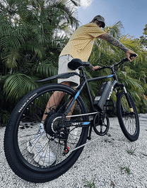 Man riding the VARUN M24-1 electric mountain bike in black on a gravel road