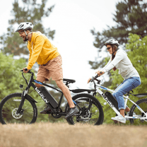 Two riders with the VARUN M24-1 electric mountain bike wearing a helmet in the forest