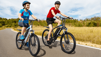 Two riders with the VARUN M24-1 electric mountain bike wearing a helmet on a road
