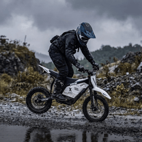 Rider taking the Vipcoo H2 electric dirt bike off-road on a road